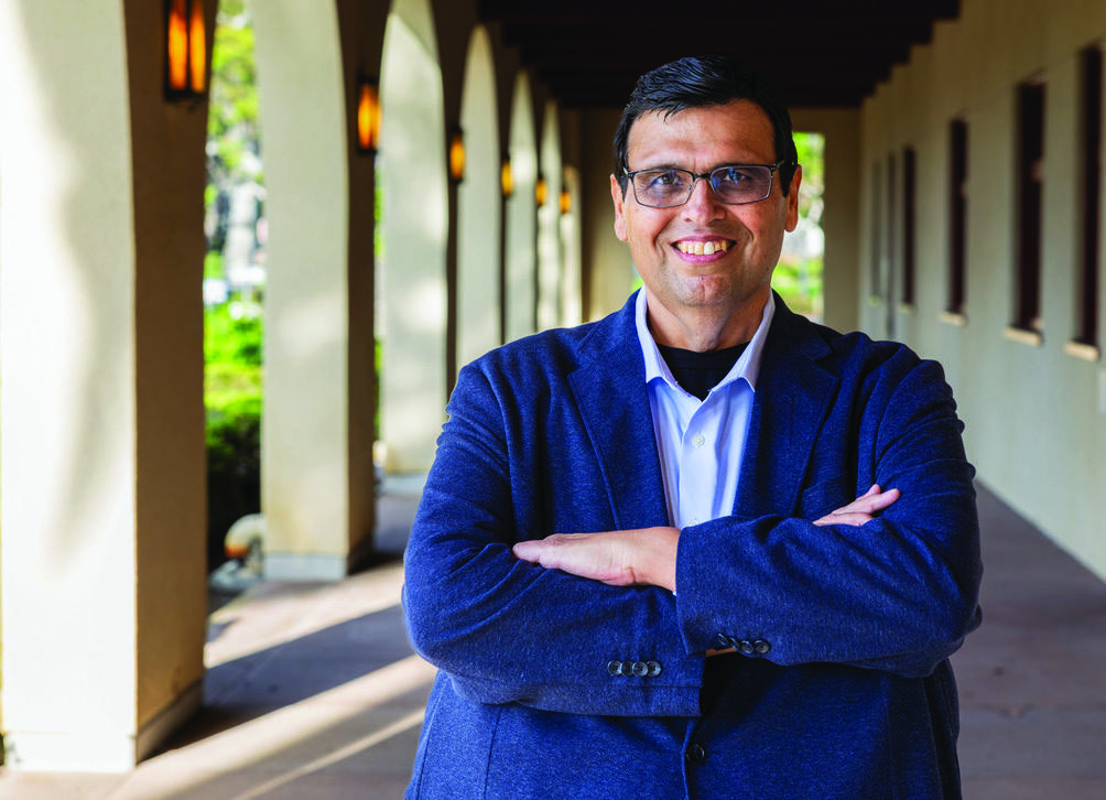 Jose Preciado smiling with his arms crossed in a covered walkway